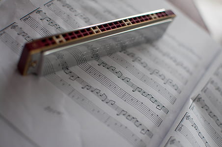 gray harmonica on top of musical sheet thumbnail