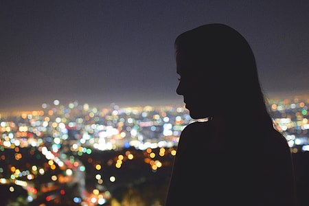 Silhouette of a woman looking over the city of Los Angeles at night thumbnail