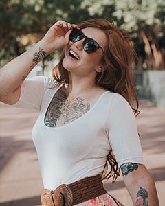 smiling woman holding her black framed sunglasses thumbnail