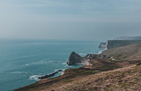 Body of Water Near Mountain Under Blue Sky at Daytime thumbnail