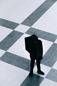 person in black jacket standing on white and gray ceramic tile floor during daytime thumbnail