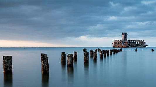 brown and black concrete house in front of body of water thumbnail