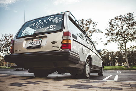white station wagon parked near green grass field and trees thumbnail