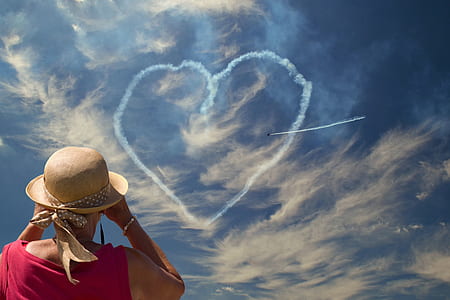 person wears red tank top looking above the sky with heart-shaped clouds thumbnail