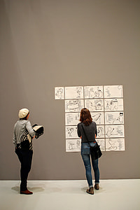 two person looking at drawings on wall thumbnail