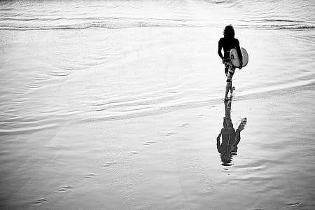 woman holding surfboard standing on seashore thumbnail