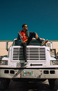 man sitting on truck during daytime thumbnail