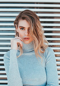 woman beside gray roller shutter wearing blue turtle neck sweatshirt thumbnail