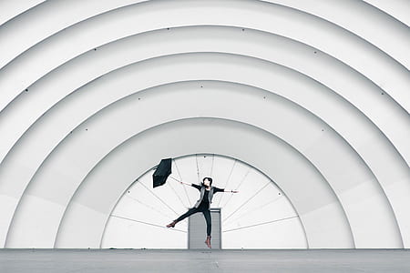 woman holding umbrella jumping near roller shutter thumbnail