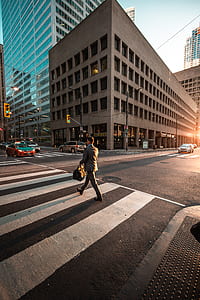 man walking on pedestrian lane beside concrete buildings thumbnail