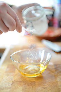 person holding clear glass jar pouring white powder on round clear glass bowl thumbnail