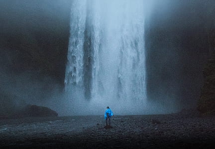 person standing on body of water looking at the waterfall thumbnail