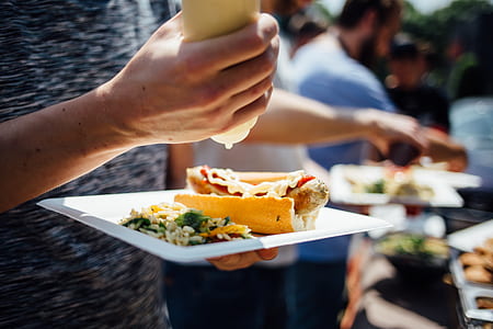 person putting sauce on hotdog thumbnail