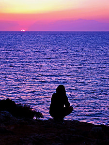 silhouette of a person standing infront of the sea during golden hour thumbnail