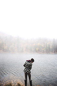 woman wearing black and white  shirt and gray pants standing beside body of water during daytime thumbnail