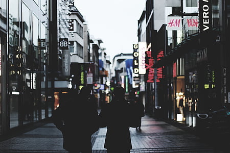 silhouette photography of two person walking between buildings thumbnail