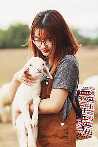 woman carryin white goat thumbnail
