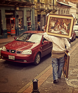 person holding paintings while walking on sidewalk thumbnail
