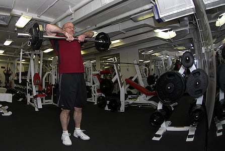 man carrying silver and black barbell inside the gym thumbnail