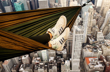 person sitting on swing above high rise buildings thumbnail