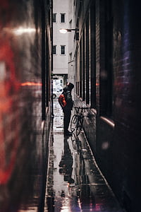 shallow focus photography of man standing beside bike thumbnail