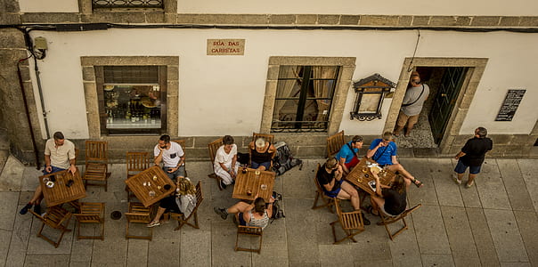 aerial photo of group of people sitting on chairs with tables beside white concrete building thumbnail