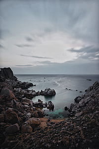 photo showing ocean with mountain rocks thumbnail