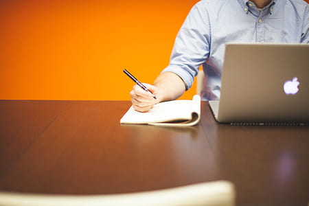 person facing laptop while holding pen thumbnail