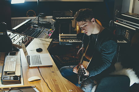 man holding brown acoustic guitar sitting near brown wooden table thumbnail