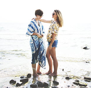 two woman standing on seashore during daytime thumbnail