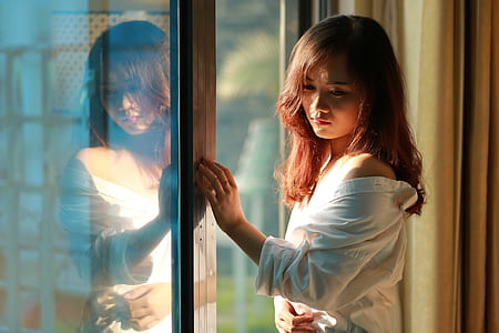 woman holding glass wall while looking downards thumbnail
