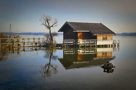 brown wooden house on body of water under white clouds thumbnail