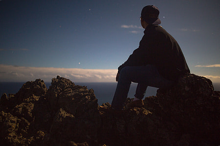 person sitting on big rock looking at the sky thumbnail