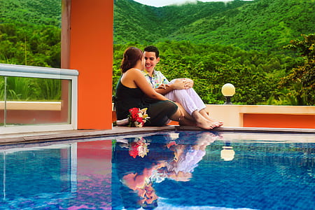 man and woman sitting in front of swimming pool thumbnail
