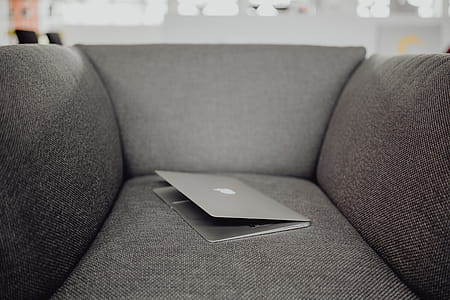 Close up view of closed laptop lying on grey armchair thumbnail