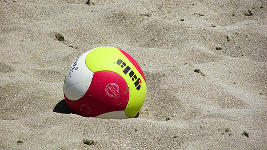 lime-green, white, and red soccer ball on beach sand thumbnail