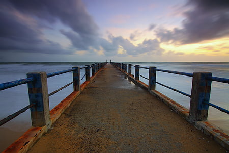 brown concrete dock beside blue ocean water under blue sky during sunrise thumbnail