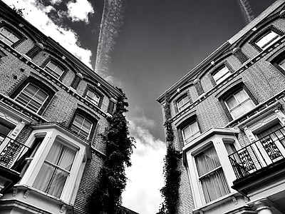 grayscale photography of buildings under sky with clouds thumbnail