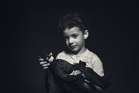 Grayscale Photo of a boy Holding Batman Plush Toy thumbnail