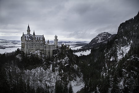 grayscale photography of white castle near mountains thumbnail