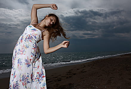 woman bending on seashore under cloudy sky thumbnail