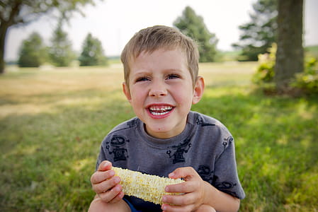 Selective Focus Photography Of Boy Holding Corn While Smiling thumbnail