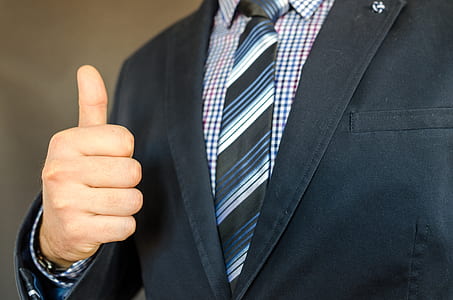 person in black coat with blue and white necktie thumbnail
