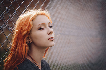 shallow focus photography of woman leaning on cyclone fence thumbnail