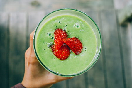 drinking glass filled with avocado shake with strawberry toppings thumbnail