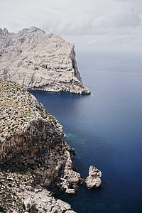white and brown rock cliffs with body of water under white sky during daytime thumbnail