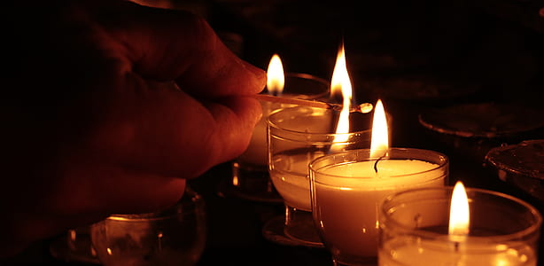 person lighting votive candles thumbnail