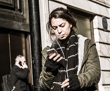 woman stander near post while holding phone thumbnail
