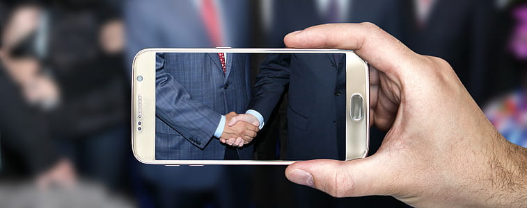 person taking a photo of two men shaking hands thumbnail