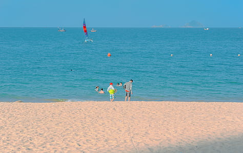 Two Kids Standing on Seashore Under Blue Sky thumbnail